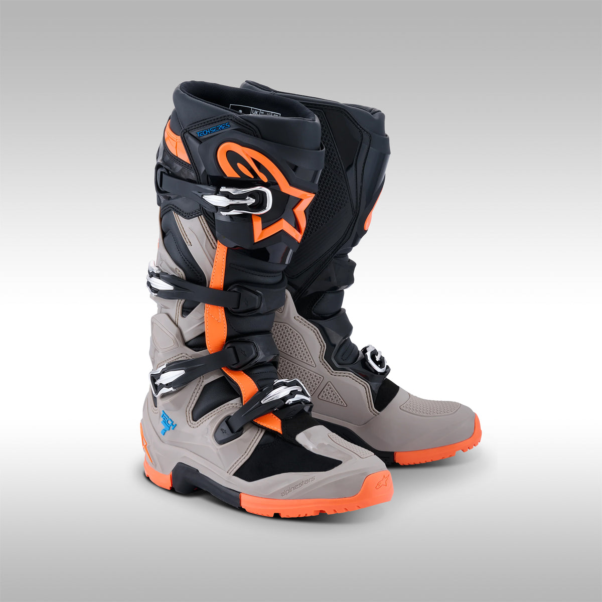 Pair of black, gray and orange Alpinestars Tech 7 Enduro offroad boots on a gray background at TMBR MOTO