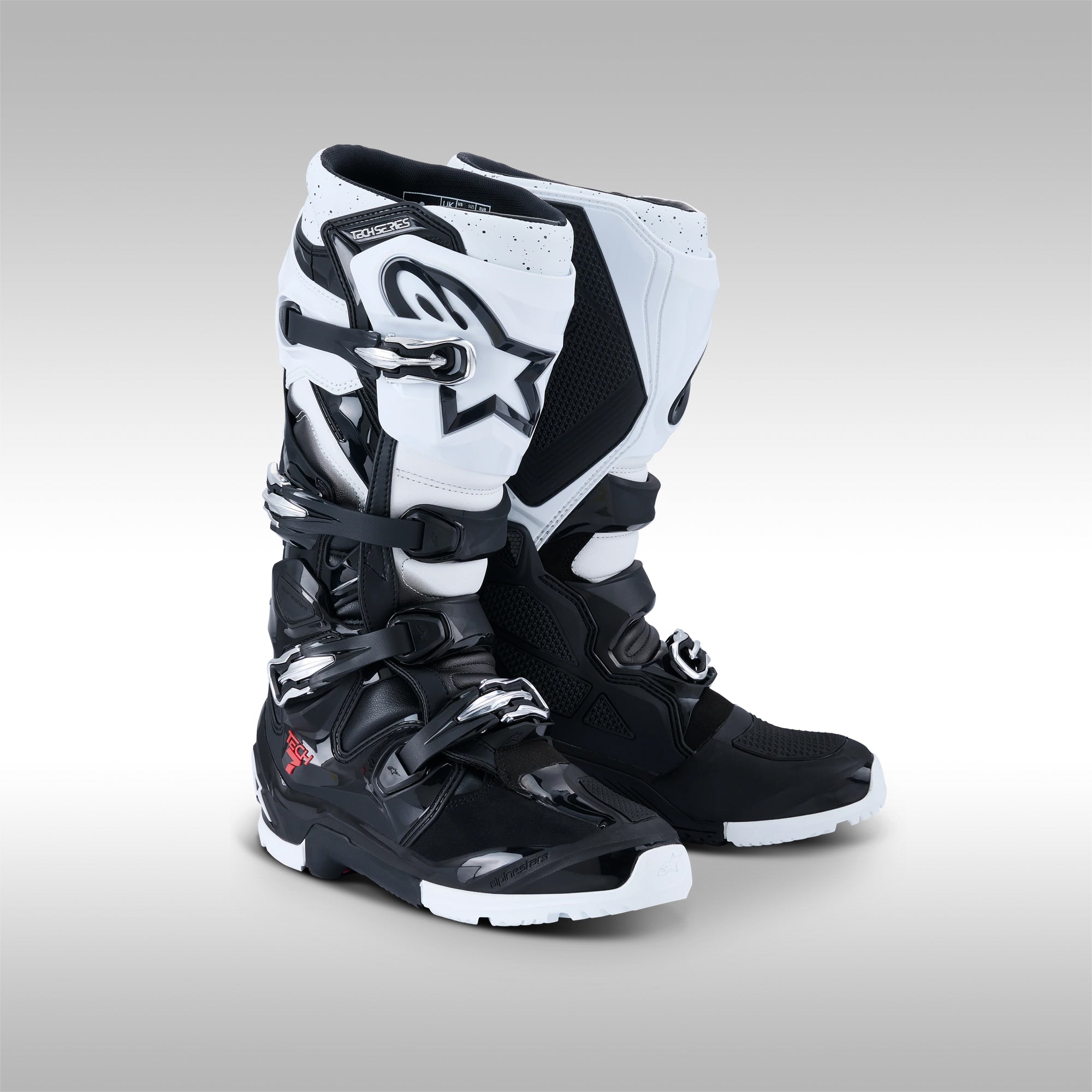Pair of black and white Alpinestars Tech 7 Enduro offroad boots on a gray background at TMBR MOTO