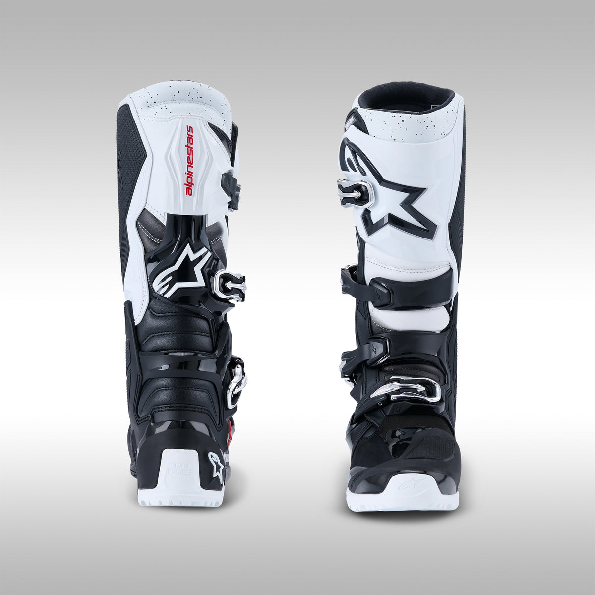 Pair of black and white Alpinestars Tech 7 Enduro offroad boots, front and rear view on a gray background at TMBR MOTO