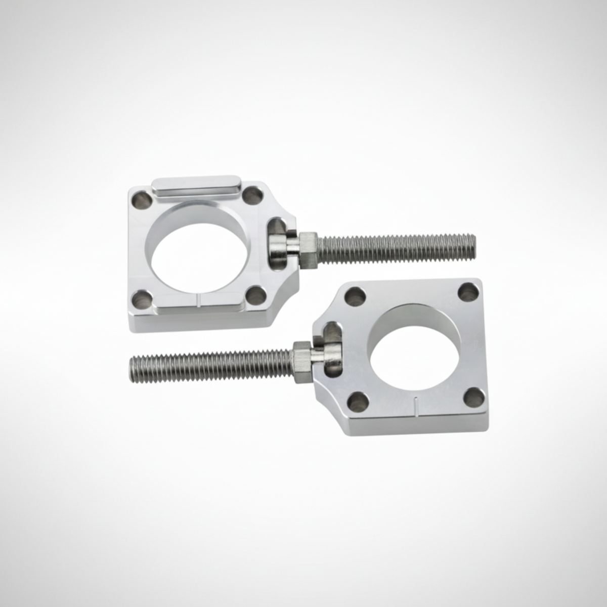Adjustable aluminum axle blocks for Honda CRF on a gray background. 