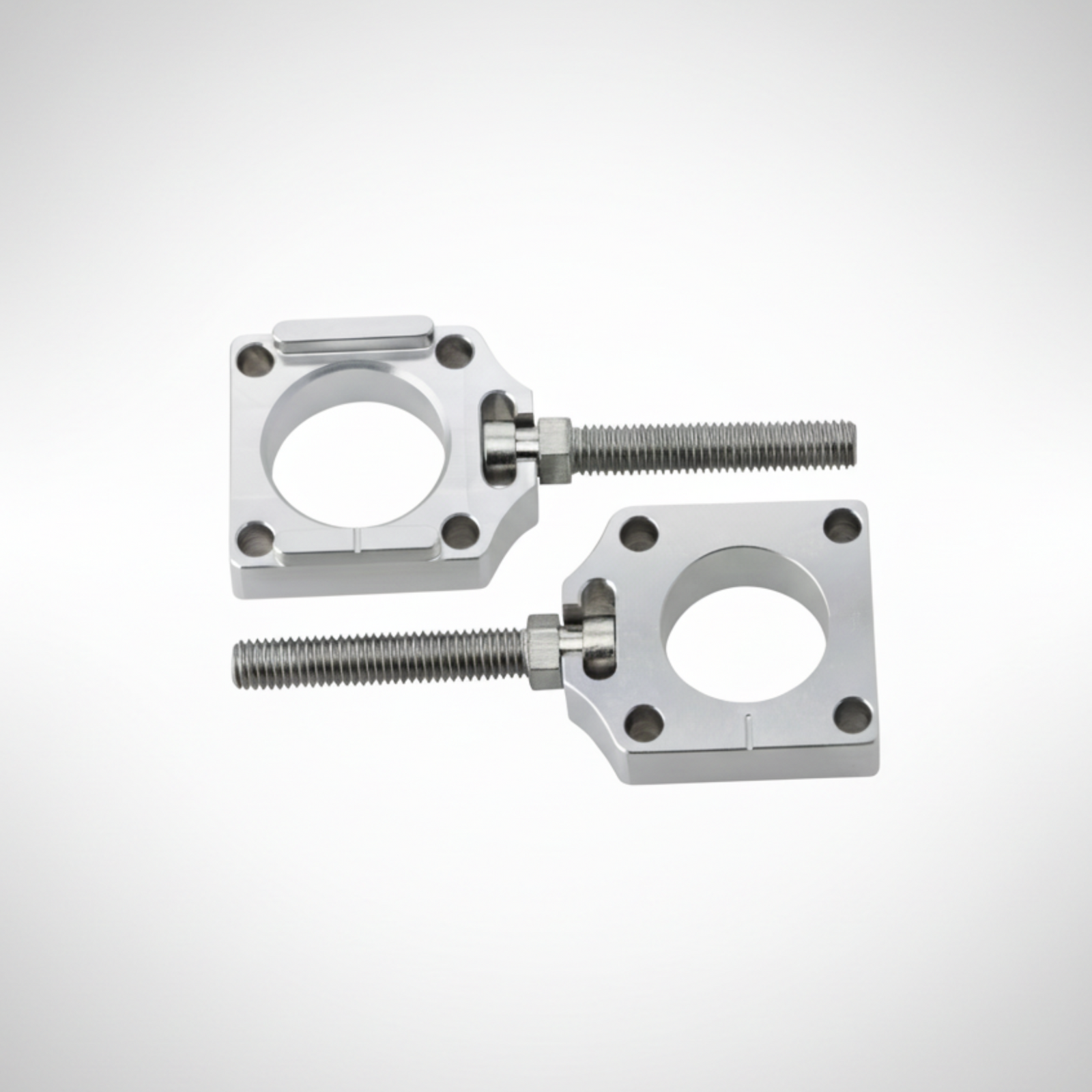 Adjustable aluminum axle blocks for Honda CRF on a gray background. 