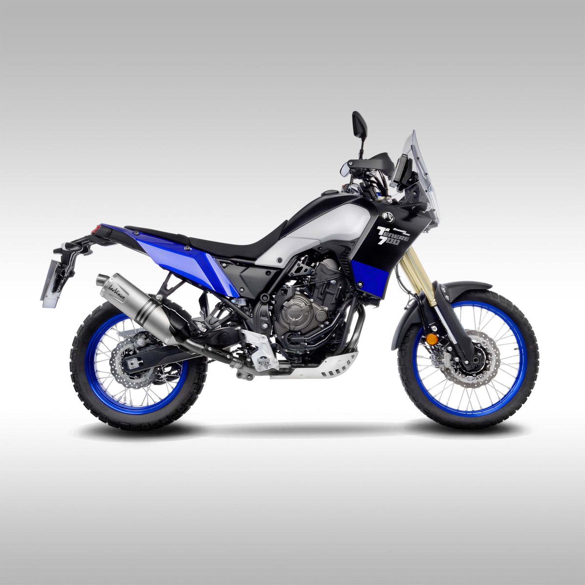 A Yamaha Tenere 700 motorcycle with a blue, black, and white color scheme, including a stainless steel header pipe.