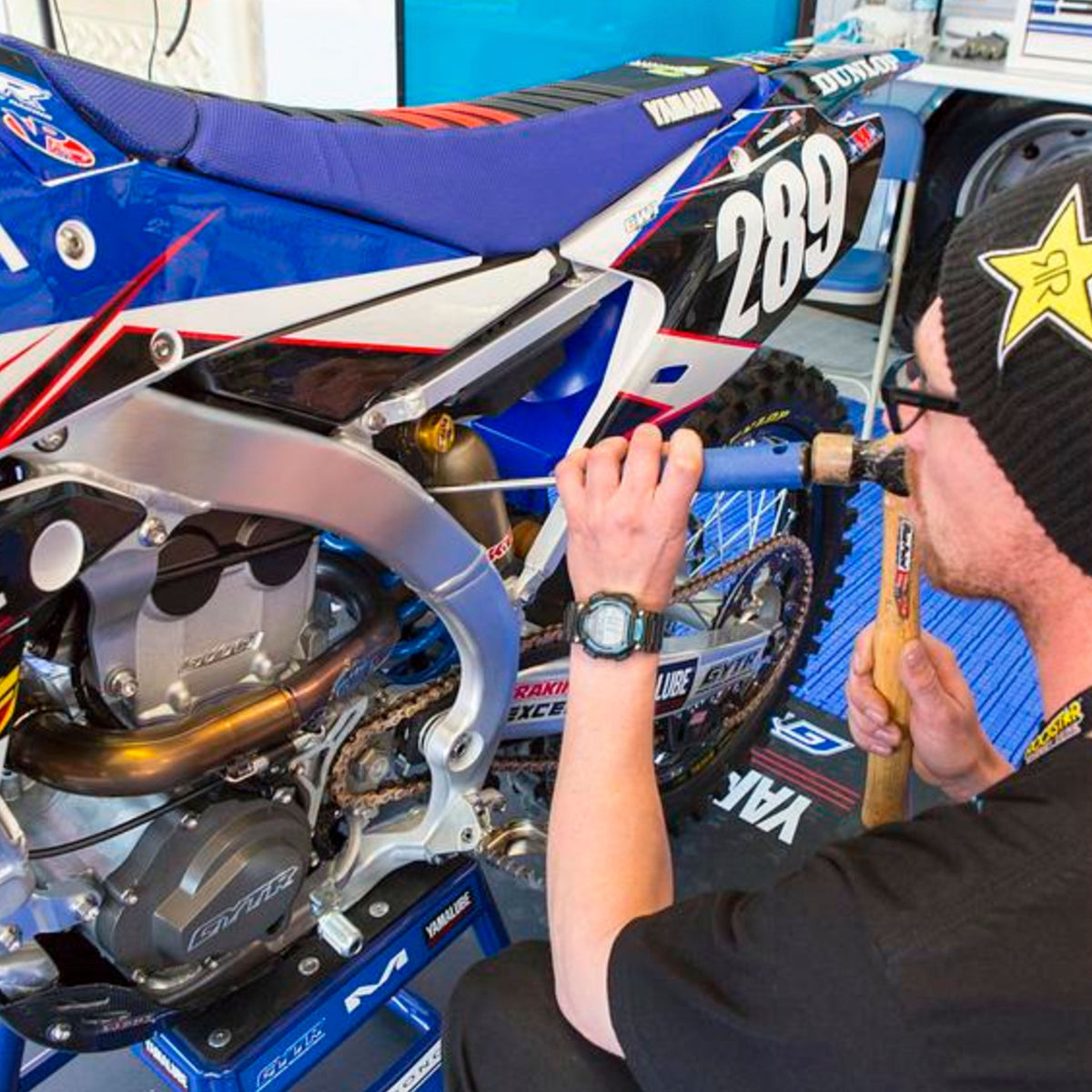 Mechanic using a Motion Pro 08-0483 shock spanner punch tool with brass tip and knurled steel handle.