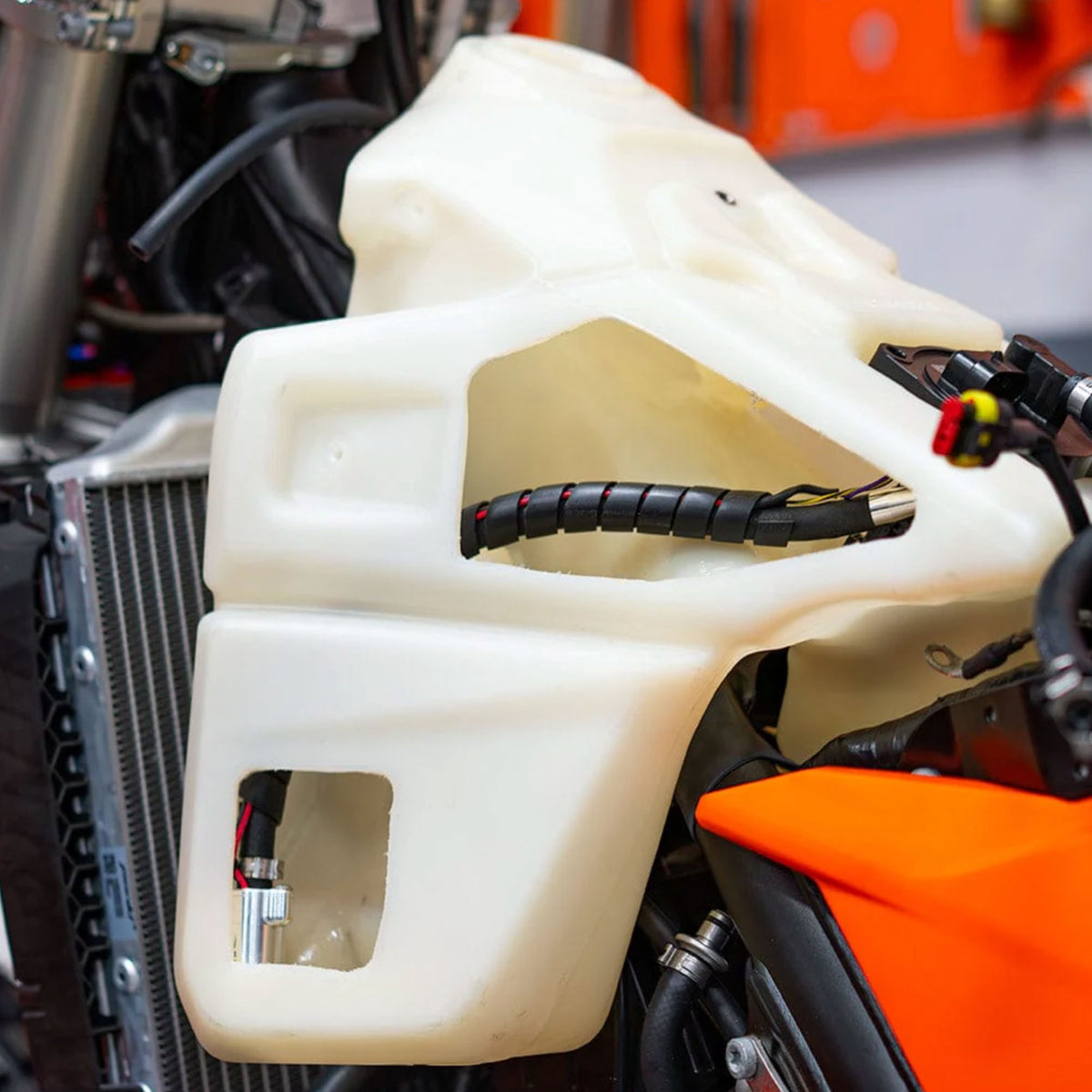 Close-up of a motorcycle's fuel tank with visible Nihilo Concepts fuel transfer pump and components.