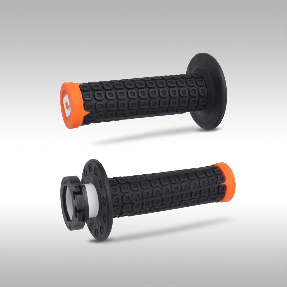 Pair of black orange ODI Nomad offroad motorcycle grips on a light gray background