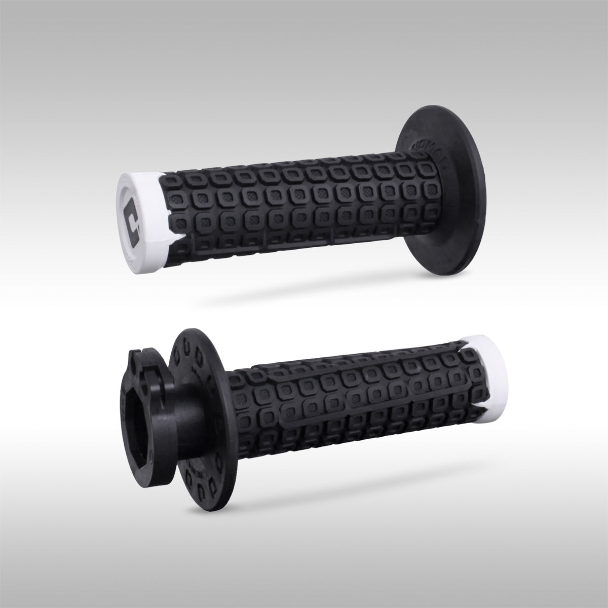 Pair of black white ODI Nomad offroad motorcycle grips on a light gray background