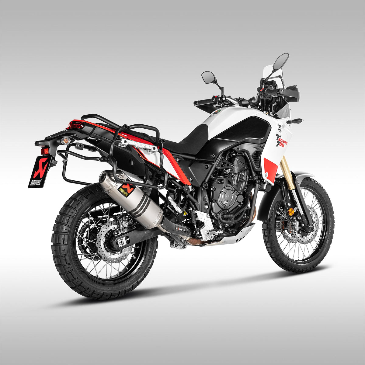 Rear 3/4 view of the titanium Akrapovic off-road slip-on exhaust installed on a red / white Yamaha Tenere 700 