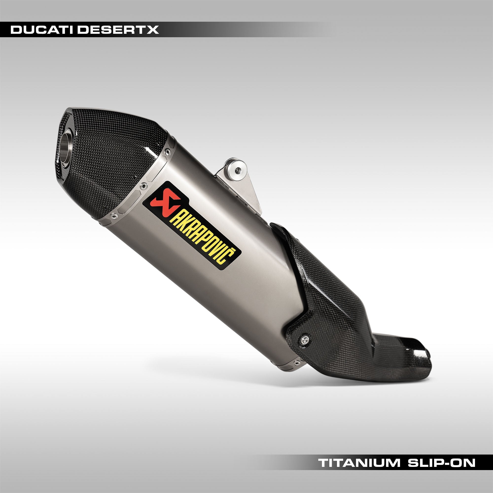 Akrapovic Titanium Slip-On Muffler for Ducati DesertX motorcycle. The muffler is primarily silver with black accents and features carbon-fibre elements, including a heatshield and end cap.