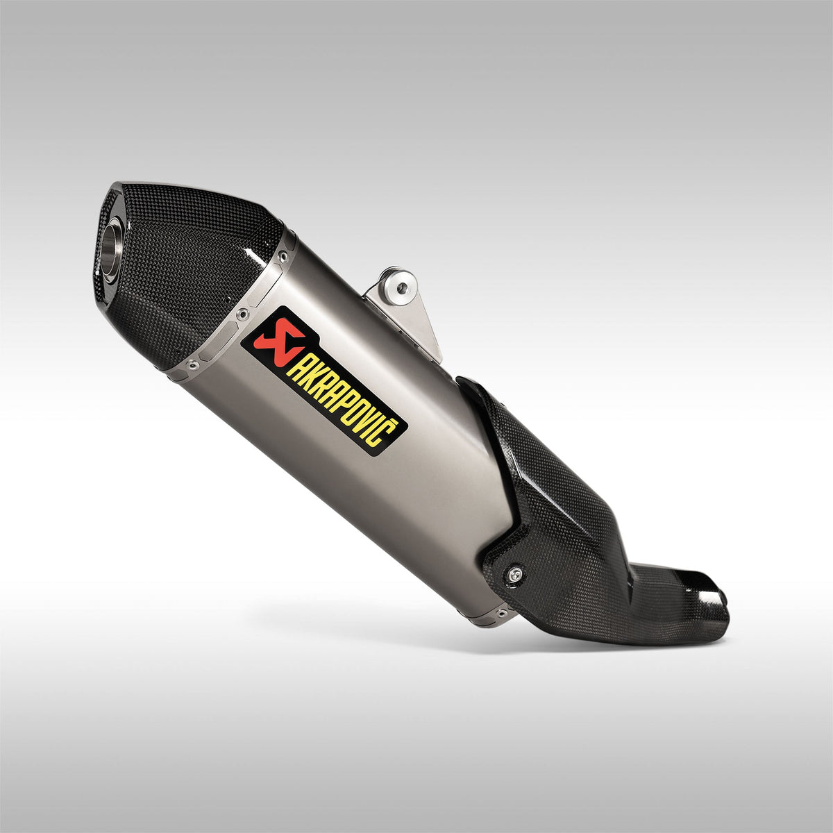 Akrapovic Titanium Slip-On Muffler for Ducati DesertX motorcycle. The muffler is primarily silver with black accents and features carbon-fibre elements, including a heatshield and end cap.