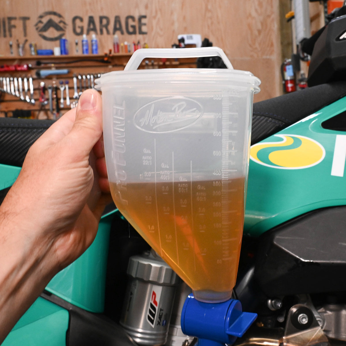 Clear plastic funnel with blue valve and long nozzle on a gray background