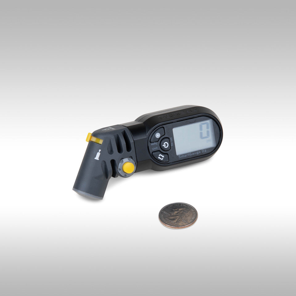 TOPEAK Smartgauge D2 compact tire pressure gauge next to a quarter for scale.